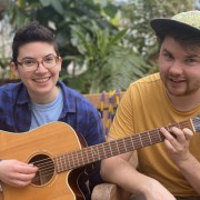 Two smiling people holding a guitar together