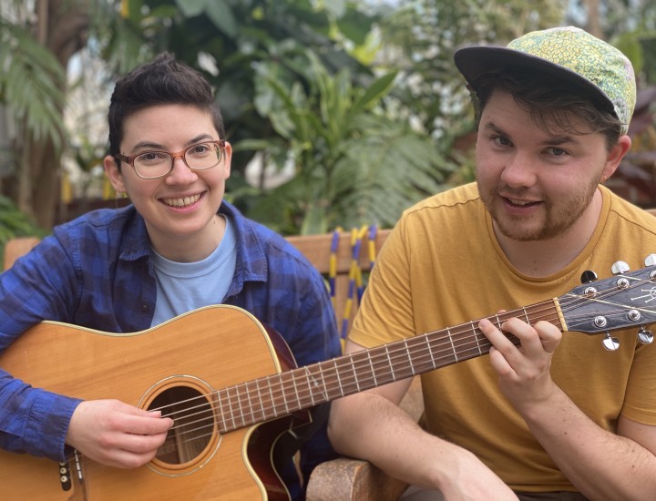 Two smiling people holding a guitar together